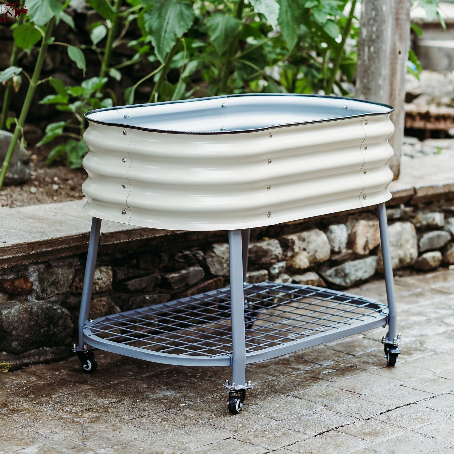 Metal planter with wheels on a patio surrounded by greenery