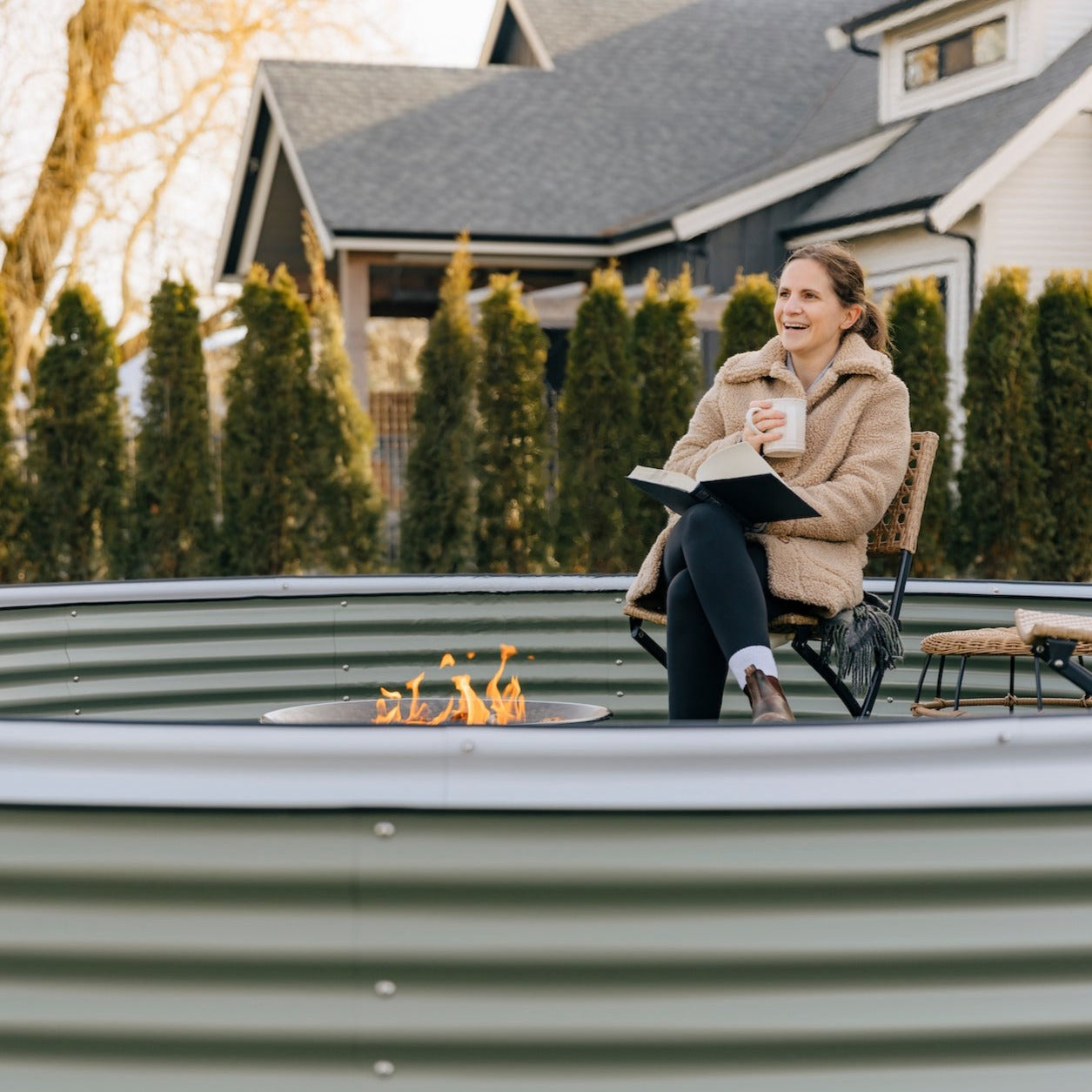 woman sitting in 17" nest garden bed in front of fire in backyard in Canada